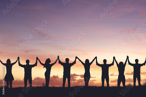 Silhouette of people holding hands against sunset background, concept of peace and victory