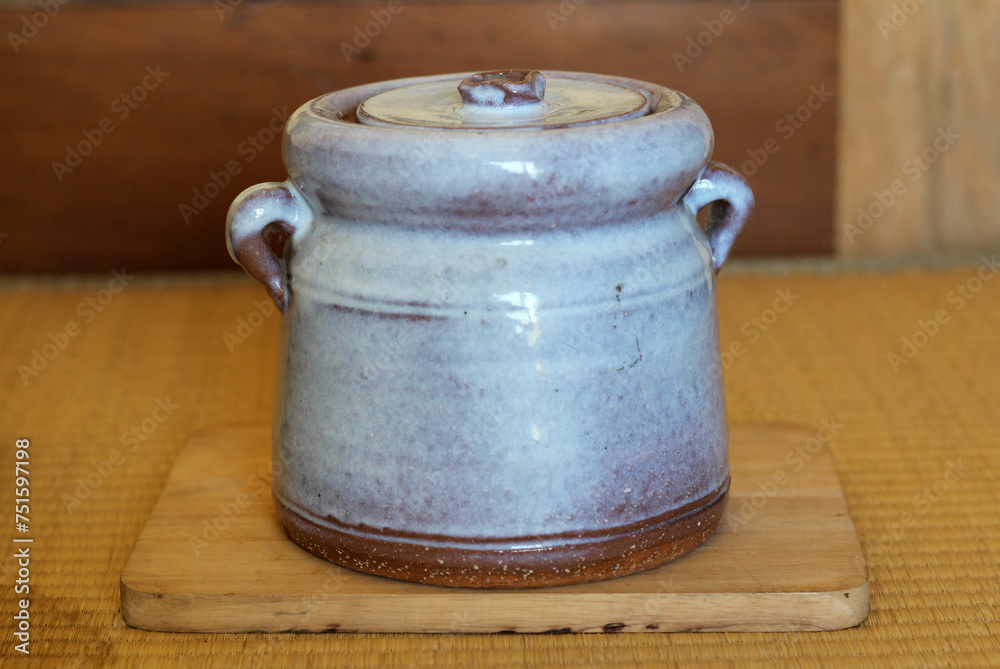 A japanese ceramic pot on a wooden tray on Japanese mat A japanese ceramic pot on a wooden tray on Japanese mat