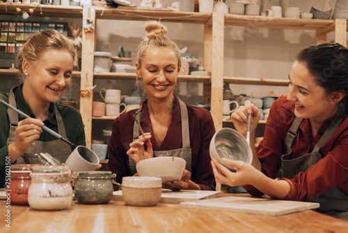 A company of three cheerful young women friends are painting ceramics in a pottery workshop. photo