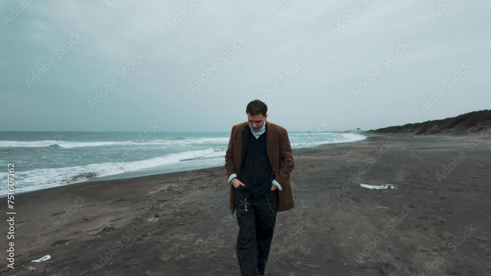 Lonely and sad well-dressed boy walks on the beach and looks at the heartbroken sea Lonely and sad well-dressed boy walks on the beach and looks at the heartbroken sea