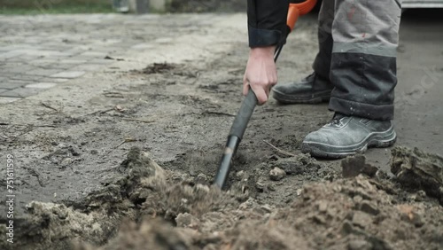 Worker Digs electric wires into the ground with a Shovel Man digs a ditch in the ground with a shovel