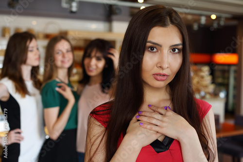 Pretty woman poses in cafe and three girls out of focus, close up