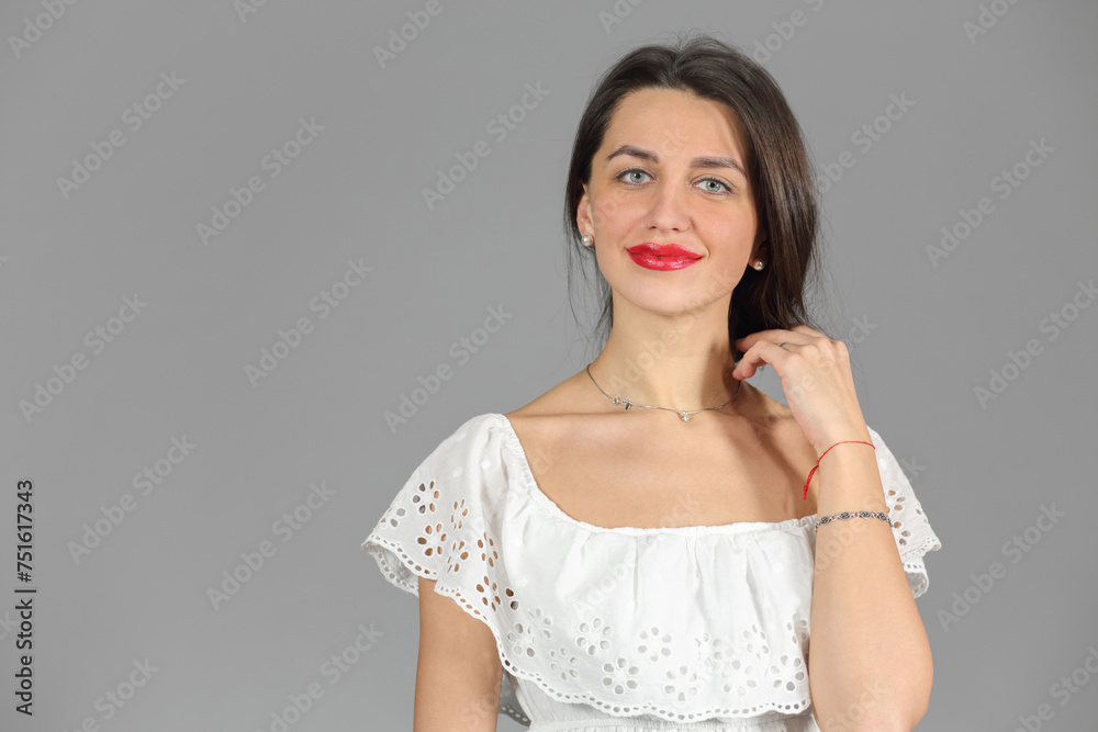 Half-length portrait of woman in white dress looking at us and smile, on gray background
