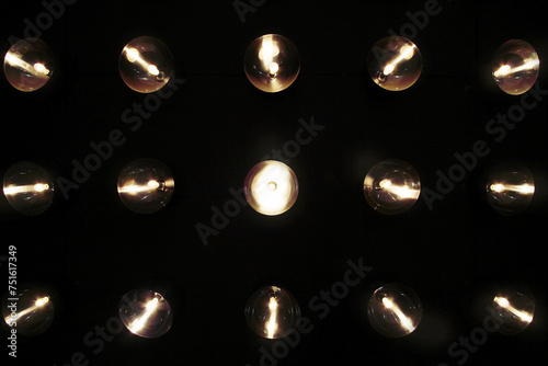 Rows of lamps on black wall in dark modern studio for illumiantion