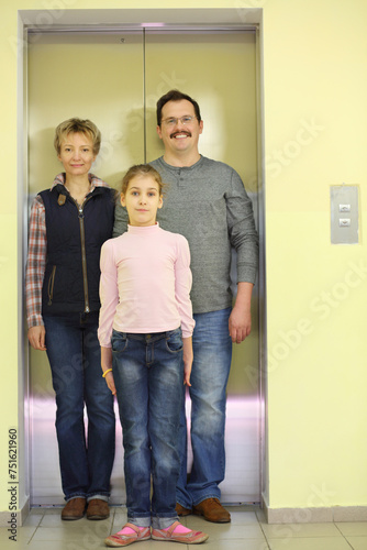 Family portrait of the three people in front of a closed elevator, focus on girl