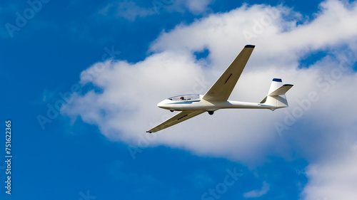 White glider plane against the blue sky. A shot of a glider airplane in flight on a sunny day.
