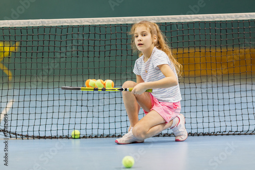 Tablou pe pânză Young female tennis player on tennis court holding balls on racket in gym