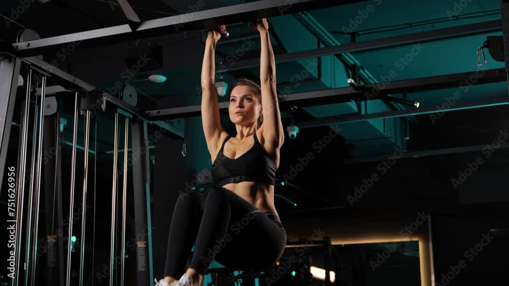 A woman is performing pull ups on a gym bar for physical fitness