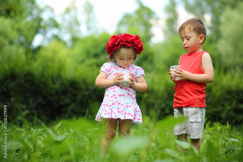 Little cute girl in wreath and boy hold milk in summer green park Little cute girl in wreath and boy hold milk in summer green park