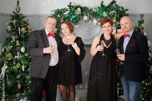 Two happy middleaged couple stand with wine during christmas evening photo