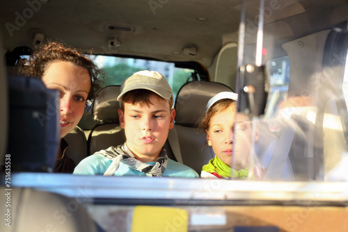 Mother with her daughter and son in the backseat of a taxi