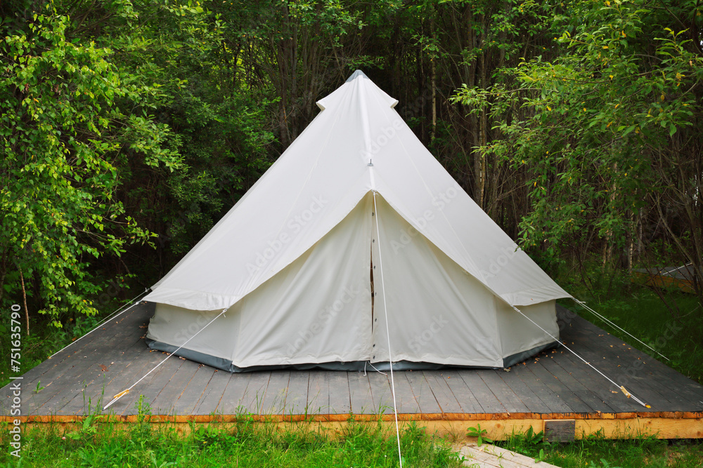 White tent for guests are hosted on wooden podium on camping