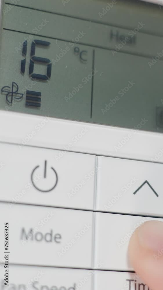Vertical video. Close-up of the wall-mounted air conditioner remote control in heating mode. Feeling hot, the man lowers the temperature. Vertical video. Close-up of the wall-mounted air conditioner remote control in heating mode. Feeling hot, the man lowers the temperature.