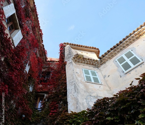 Beautiful corner of old house rustic house with wooden shutters and red wall plants in Eze Village, French Riviera 