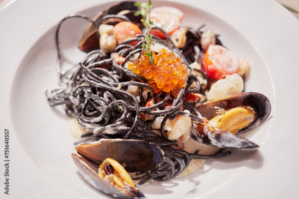Mussels, red caviar and vegetables mix on white plate