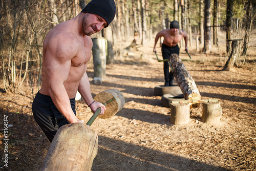 Fotografija Two jocks bulk up with a wooden barbell topless in the autumn forest