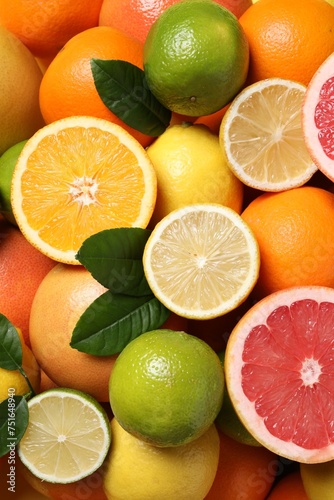 Different fresh citrus fruits and leaves as background  top view