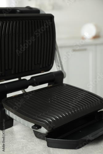 Electric grill on grey textured table in kitchen, closeup. Cooking appliance