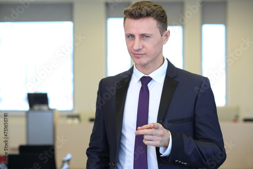 Businessman with distrustful look pointing at camera in the office photo