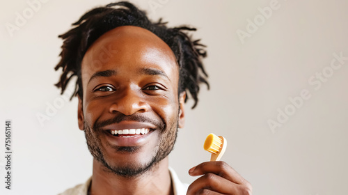 A cheerful young black man is doing a facial massage with a natural bristle brush, an instrument used in beauty and wellness treatments. Soft masculinity, daily self-care