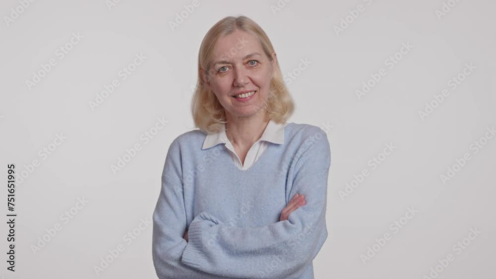 A blond woman in electric blue sweater, smiling with arms crossed A blond woman in electric blue sweater, smiling with arms crossed