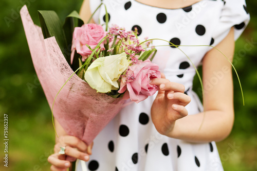 Body and hands of girl who holds bunch of flowers outdoor. photo