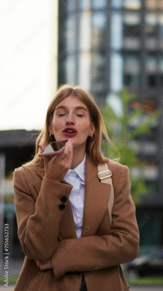 Vertical view of young smiling business woman in jacket with coffee cup using mobile phone Vertical view of young smiling business woman in jacket with coffee cup using mobile phone