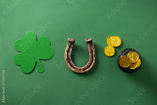 St. Patrick's day concept with clover leaf, golden coins and horseshoe on green background. View from above. Wooden block with text - Patricks day.