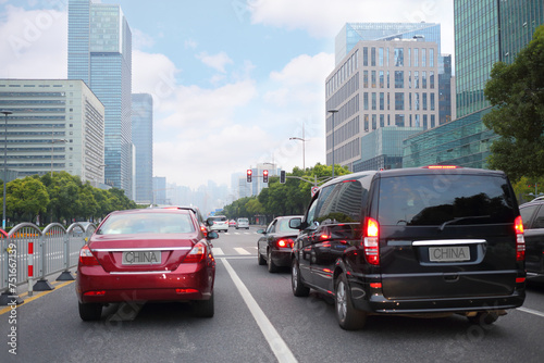 Many cars move on city road amonf tall buildings in Shanghai, China