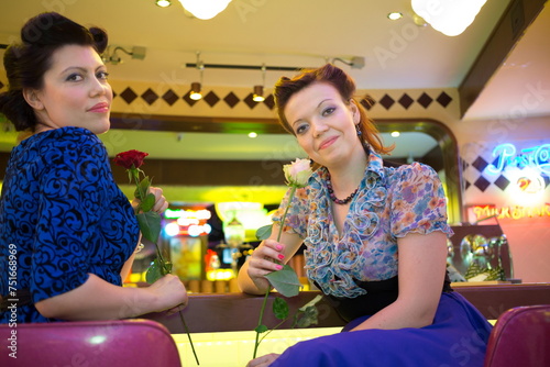 Two beautiful women an bar with roses in hands photo