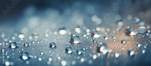 Close up view of water droplets resting on a window, reflecting light and creating a shimmering effect. The droplets vary in size and shape, adding texture to the glass surface.