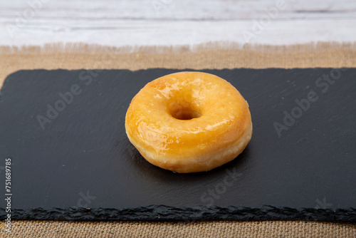 Canvas Print Steaming cup of coffee cozies up to a plate of freshly glazed donuts