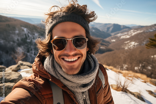 Exuberant young man taking a selfie on a mountain trail in winter.