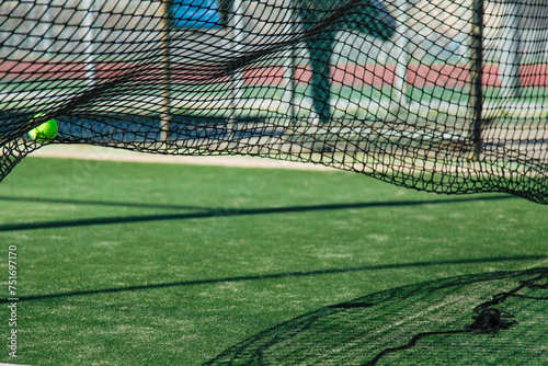 Tennis ball caught in a net over synthetic grass