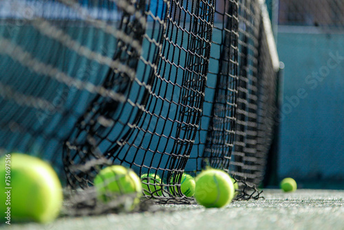 Tennis balls beside a net on a sunlit court