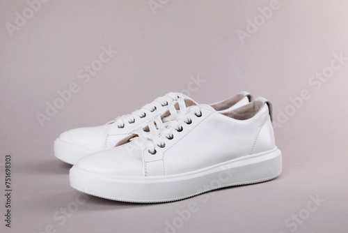 Pair of stylish white sneakers on grey background