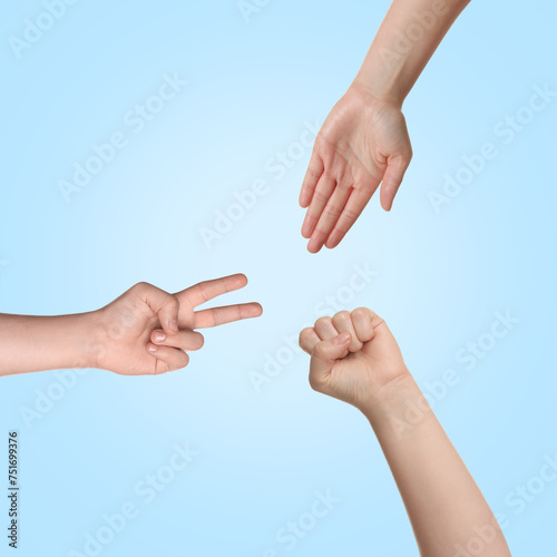 People playing rock, paper and scissors on light blue background, top view © New Africa