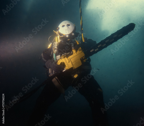 Commercial diver holding chainsaw underwater wearing mask