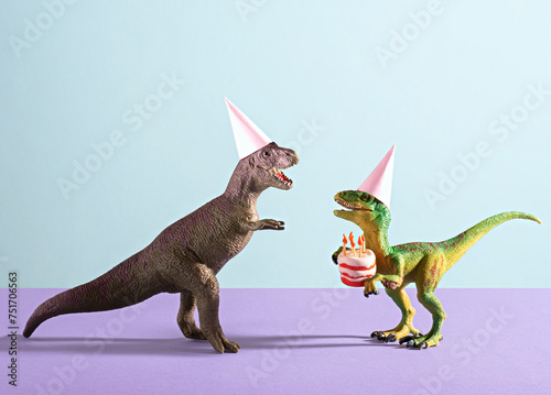 Fototapeta Naklejka Na Ścianę i Meble -  Cute happy dinosaurs in birthday hats holding cake with flaming candles on blue violet background.