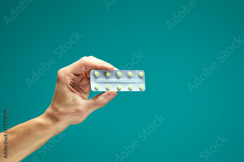 Human hands holding blister of pills in hand isolation on green background. Treatment, healthcare, painkiller, pharmacology, medicine concept.