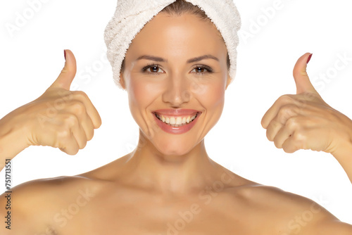 Beauty portrait of a cheerful attractive half naked woman with a towel wrapped around her head with toothy smile and thumbs up isolated over white background