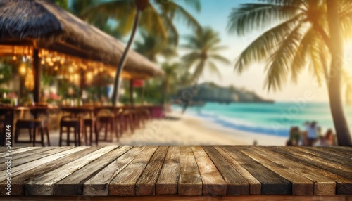 wooden table in the foreground and soft focus summer beach and a bar in the blurred background tropical resort banner as a tropical holiday concept