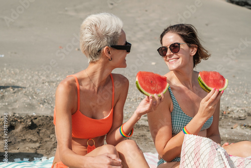 Two young friends on a day at the beach eating fresh fruit. Concept: enjoy, fun #751719958