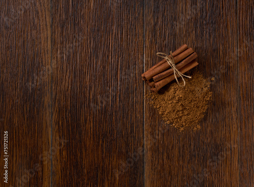 Fototapeta Naklejka Na Ścianę i Meble -  cinnamon sticks and cinnamon powder on a brown wooden table, top view.