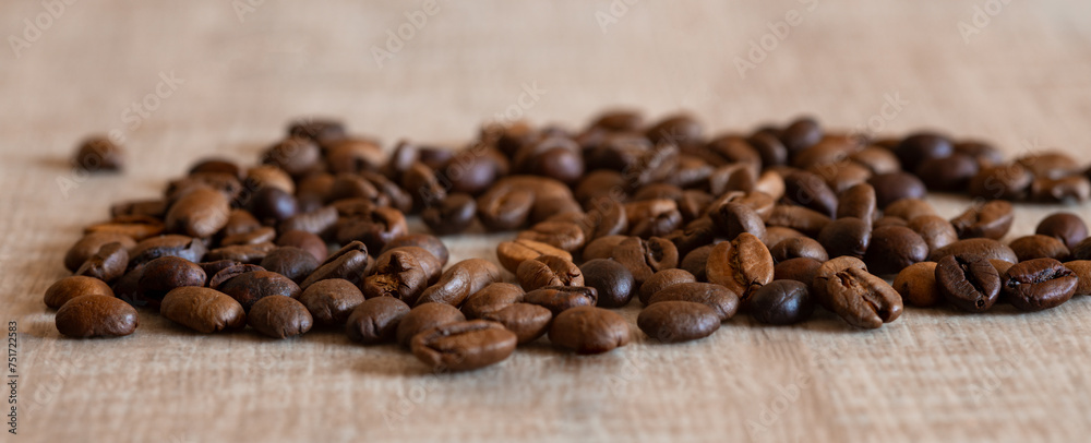 Coffee beans on a wooden table, selective focus, close-up, macro. Arabica or robusta coffee is scattered on the table, a banner. Coffee beans on a wooden table, selective focus, close-up, macro. Arabica or robusta coffee is scattered on the table, a banner.