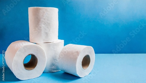 several rolls of toilet paper lying on blue background copy space