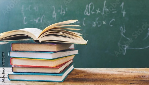 education and reading concept group of colorful books on the wooden table in the classroom blackboard background