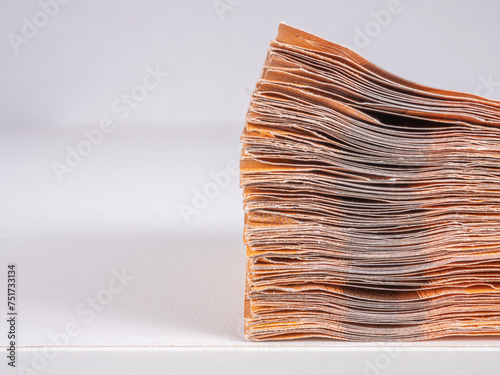 A stack of euro banknotes on the edge of a table, close-up, side view, on a light background. 