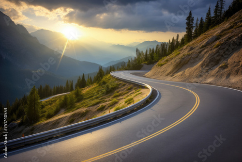 Winding asphalt road cuts through the mountain, with the sun shining through the clouds. High quality photo