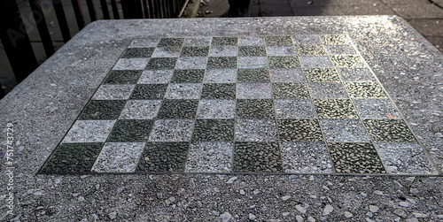 chessboard on a stone table in a public park (brooklyn new york city) chess board checkered squares pattern close up detail black and white game outdoors